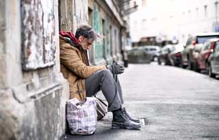 A homeless man sitting in a doorway.