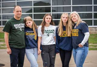 From left to right: Pat Damer and his daughters Sophia, an Oxford High School senior; Isabella, a Michigan State University junior; Mia, an Oxford freshman; and his wife Jeanne in front of Oxford High School. Sophia survived the Oxford shooting and Isabella survived the MSU shooting. Photo credit Valaurian Waller.