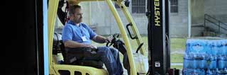 Man using a forklift to move a pallet of bottled water at Catholic Charities of Shiawassee and Genesee Counties