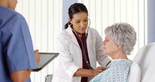 Doctor examining an elderly female patient using a stethoscope