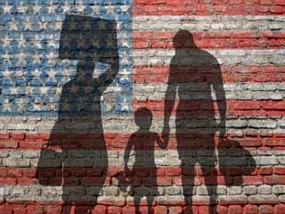 Silhouette of immigrant family on a weathered brick wall painted with the American flag