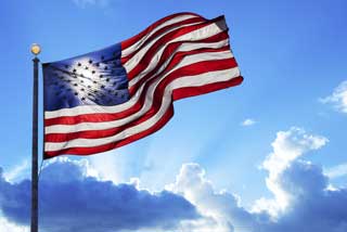 American flag waving in the wing against a bright blue sky