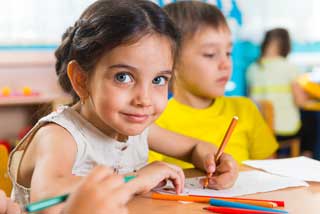 A young female student looks at the camera while working on her school work