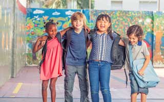 Four children linking arms and laughing in a schoolyard