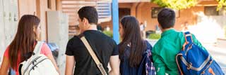 Four high school students walking outside of their school