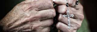 Close-up of a woman's hands as she prays the rosary