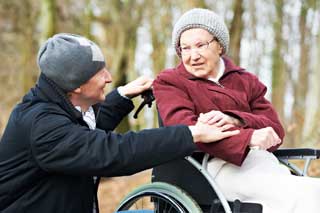 A man comforts an elderly woman in a wheelchair