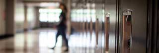 A student walks across a hallway lined with lockers at school