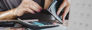 A woman looks for money in a wallet that is obviously empty