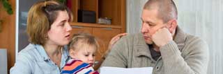 A young mother and father hold their small daughter while figuring out their financial situation