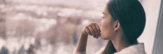 A woman stares contemplatively out of the window