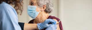 An elderly woman receives the COVID-19 vaccine from her health practitioner