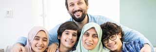 A happy Muslim family poses for a portrait on the sofa