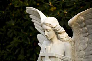 An angel carved from white stone gazes downward, wings spread