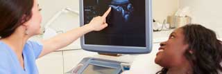 A nurse pointing to an ultrasound image of a pregnant woman's child.