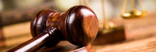 Closeup of a judge's gavel with the scales of justice in the background.