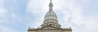 Exterior of the Michigan State Capitol Building in Lansing on a cloudy day.