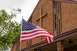 The American flag waving in the wind in front of a church during the Primary Election in 2024