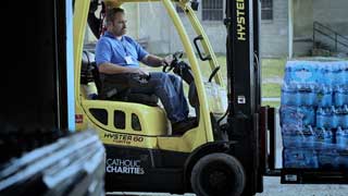 Man using a forklift to move a pallet of bottled water at Catholic Charities of Shiawassee and Genesee Counties