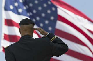 Soldier saluting an American flag waving in the wind