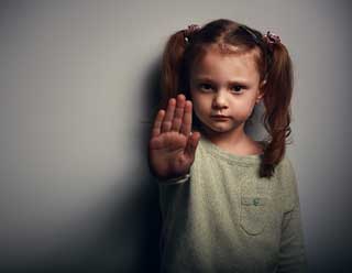Dramatic photo of a small girl with pigtails holding up her hand in a 