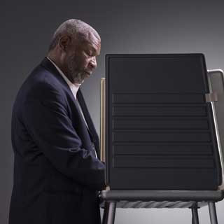 A man casting his vote in a voting booth