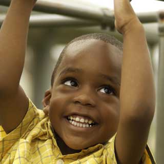 An African-American boy smiles while playing at a playground