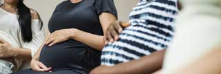 Several pregnant women, smiling and holding their bellies