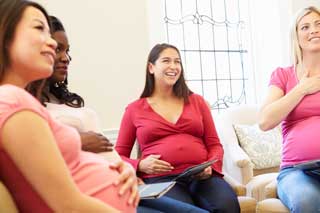 Four pregnant women talking and smiling