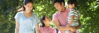 A smiling mother and father and their two children walk along a nature trail