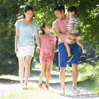 A smiling mother and father and their two children walk along a nature trail