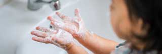 A young girl washing her hands in a bathroom sink