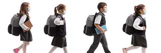Four children wearing protective masks and school uniforms walking in single file