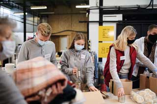 A group of volunteers wearing face masks working at a food bank and donation center