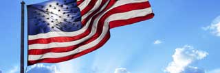 The American flag waving in the wind while the sun breaks through the clouds behind it