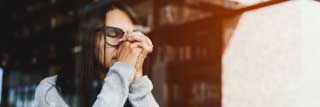 A woman closes her eyes and clasps her hands in prayer over her Bible