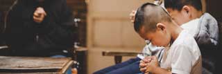 A mother and her three childrew bow their heads in prayer