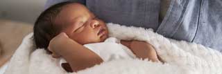 A newborn baby being craddled in his father's arms