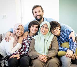 A happy Muslim family poses for a portrait on the sofa