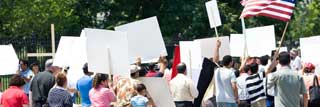 People marching, carrying protest signs, and waving an American flag