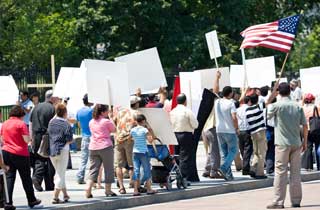 People marching, carrying protest signs, and waving an American flag