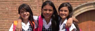 Three smiling girls in school uniforms with their arms around each other