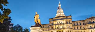 The exterior of the Michigan State Capitol building, lit up at dusk.
