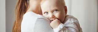 A mother holding her baby against her chest.