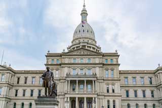 Exterior of the Michigan State Capitol Building in Lansing on a cloudy day.