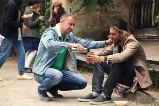 A man pours a cup of coffee for a man less fortunate than himself.