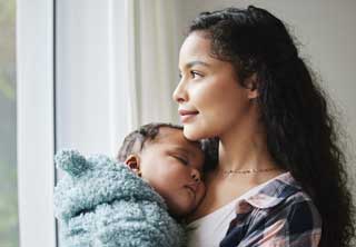 A mother holding her child, gazing out the window