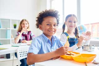 Smiling school children eating lunch