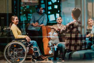 A businesswoman in a wheelchair having meeting with her team at a modern office.